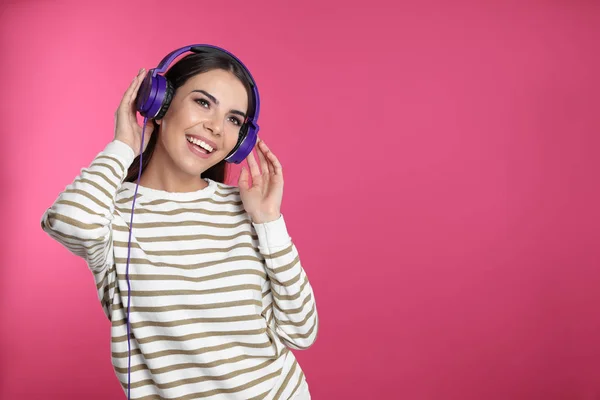Ελκυστική νεαρή γυναίκα που απολαμβάνει μουσική στα ακουστικά σε χρώμα φόντο. Χώρος για κείμενο — Φωτογραφία Αρχείου