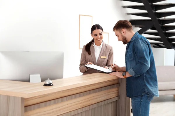 Recepcionista profesional trabajando con el cliente en el escritorio en un hotel moderno —  Fotos de Stock