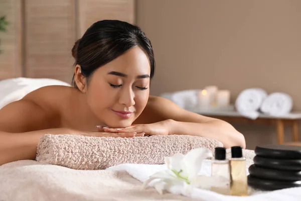 Mulher asiática bonita deitada na mesa de massagem no salão de spa. Espaço para texto — Fotografia de Stock