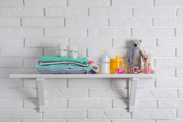 Estante con accesorios para bebés en la pared de ladrillo blanco — Foto de Stock