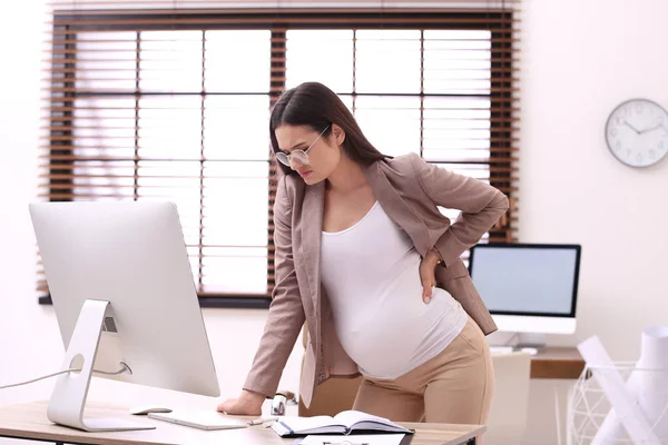 Jonge zwangere vrouw die lijdt aan pijn tijdens het werken in het kantoor — Stockfoto