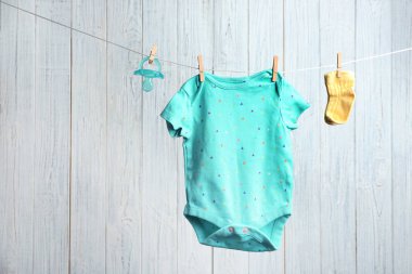 Bodysuit, çorap ve ahşap arka plan karşı çamaşır hattı üzerinde emzik çifti, metin için alan. Bebek aksesuarları
