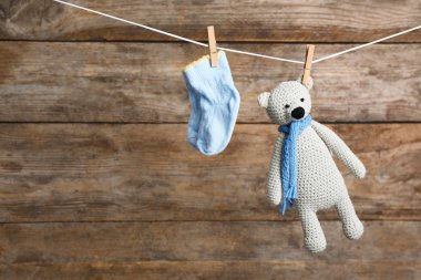 Ahşap arka plan, metin için alan karşı çamaşır hattı üzerinde çorap ve oyuncak ayı çifti. Bebek aksesuarları