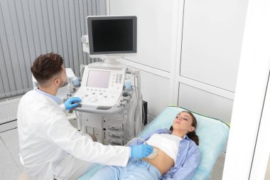 Doktor, klinikte hastanın karnını ultrasonla muayene ediyor.