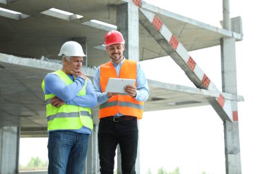 Şantiyede güvenlik ekipmanlarında tablet ve foreman ile profesyonel mühendis. Metin için alan