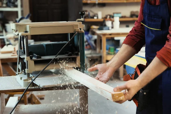 Working man using thickness planer at carpentry shop, closeup — Stock Photo, Image