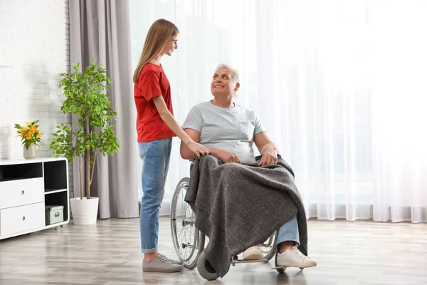 Tiener meisje met grootvader in rolstoel thuis — Stockfoto