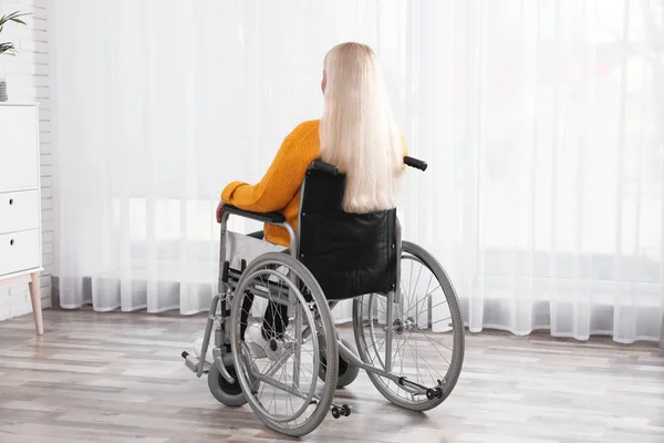 家の窓の近くの車椅子に座っている成熟した女性 — ストック写真