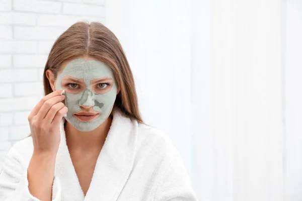 Gyönyörű nő eltávolítása agyag maszkot az arcát beltéri — Stock Fotó
