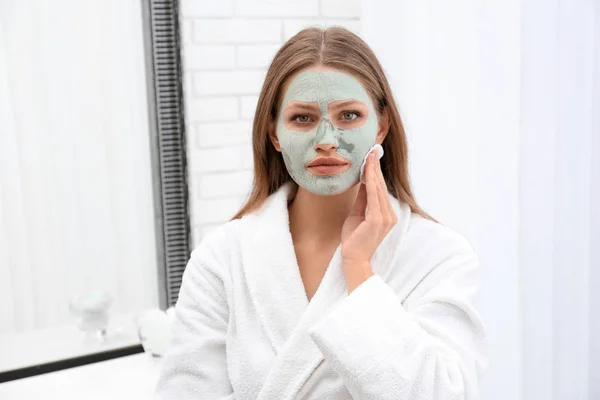 Krásná žena Odstraňuji domácí hliněnou masku z obličeje uvnitř — Stock fotografie