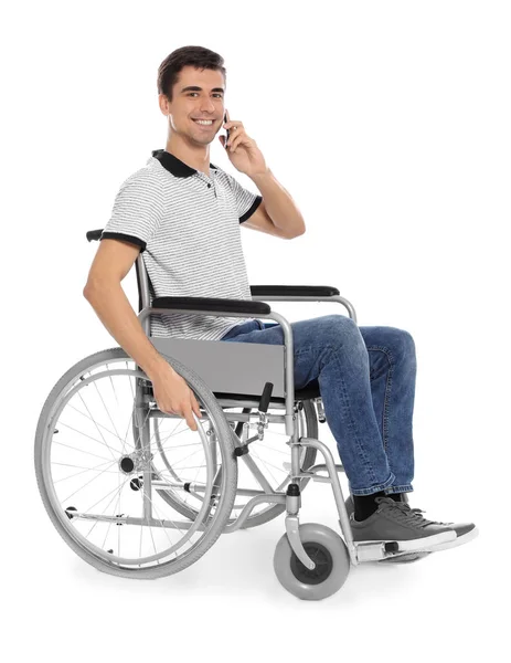 Mladý muž v invalidním vozíku, který mluví mobilním telefonem izolovaným na bílém — Stock fotografie
