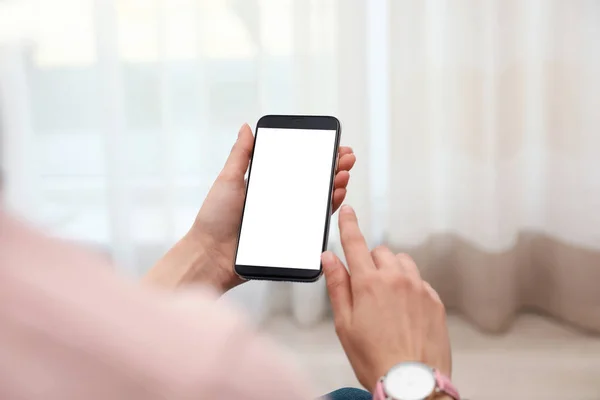 Mulher segurando smartphone com tela em branco dentro de casa, close-up de mãos. Espaço para texto — Fotografia de Stock