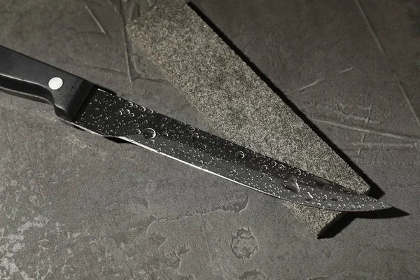 Нож и заточка камня на сером каменном фоне — стоковое фото