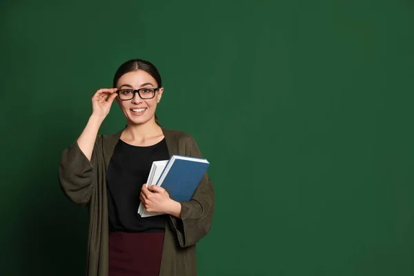 Porträtt av ung lärare med böcker på grön bakgrund. Utrymme för text — Stockfoto