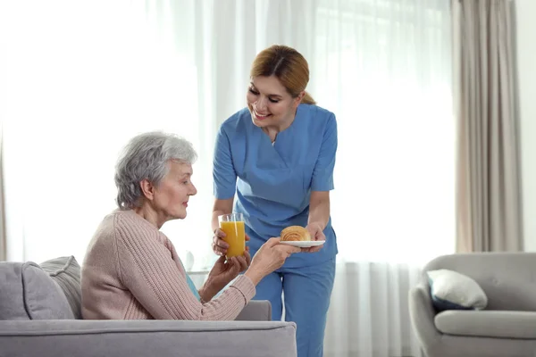 Enfermera que sirve el desayuno a la anciana en el interior, espacio para el texto. Asistencia a personas mayores — Foto de Stock