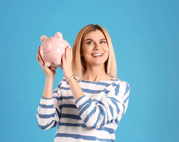 Mulher com banco porquinho no fundo de cor — Fotografia de Stock