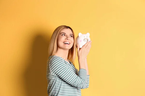 Mujer con alcancía sobre fondo de color —  Fotos de Stock