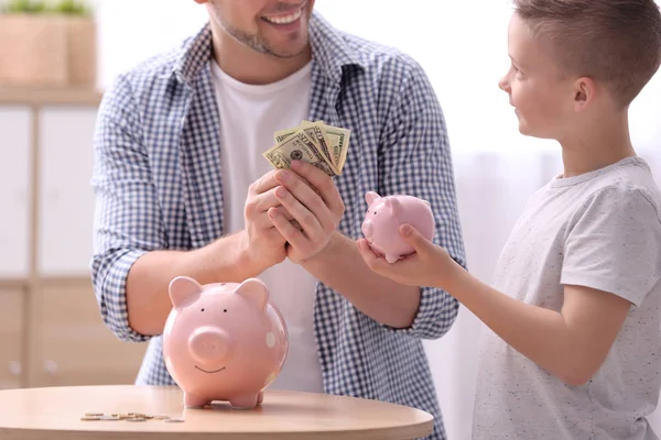 Family with piggy banks and money at home — Stock Photo, Image