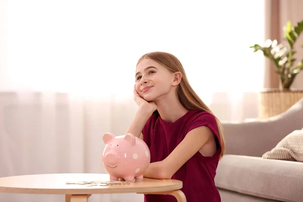 Teen girl with piggy bank and money at home — Stock Photo, Image