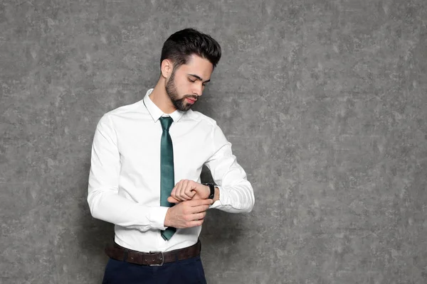 Retrato de empresário confiante olhando para relógio de pulso em fundo cinza. Espaço para texto — Fotografia de Stock