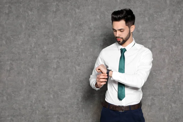 Porträtt av trygg affärsman som tittar på armbandsur på grå bakgrund. Utrymme för text — Stockfoto