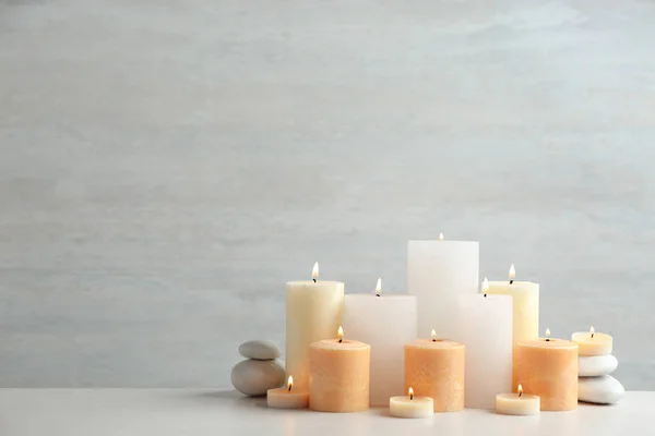 Bela composição com velas na mesa contra fundo claro — Fotografia de Stock