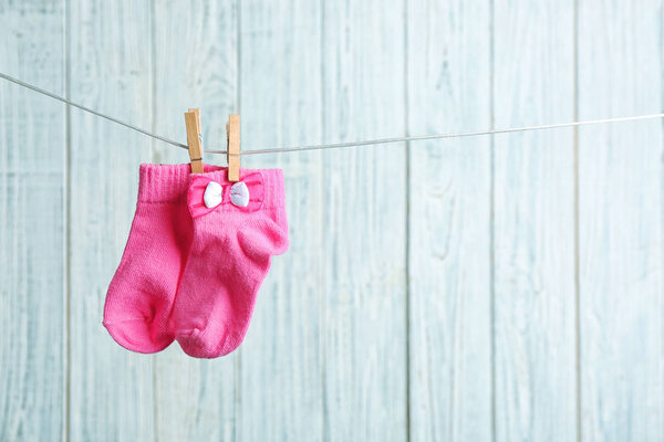 Pair of socks on laundry line against wooden background, space for text. Baby accessories