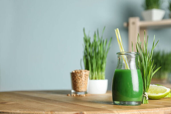 Bottle of juice and fresh wheat grass on table. Space for text