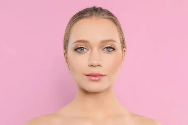 Portrét mladé ženy s krásnou tváří na růžovém pozadí — Stock fotografie