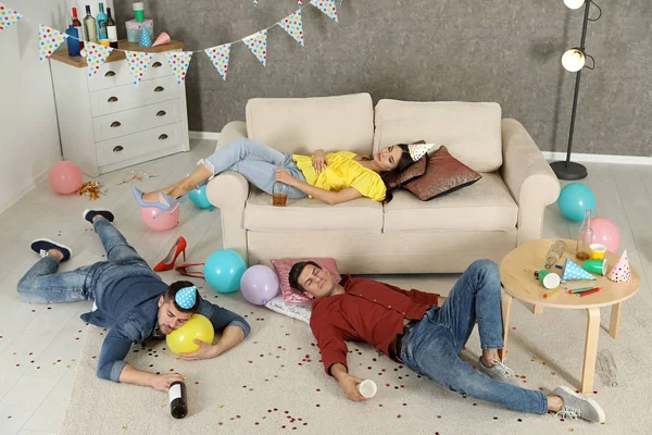 П'яні друзі сплять у безладному номері після вечірки — стокове фото