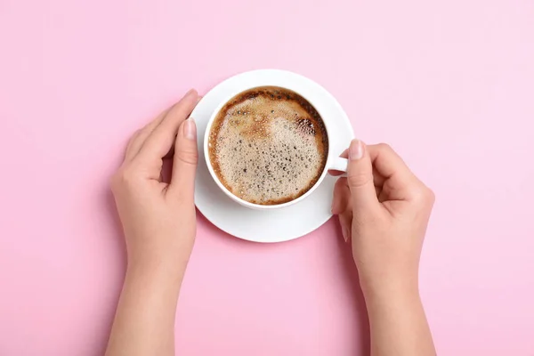 Женщина с чашкой кофе на розовом фоне, вид сверху — стоковое фото