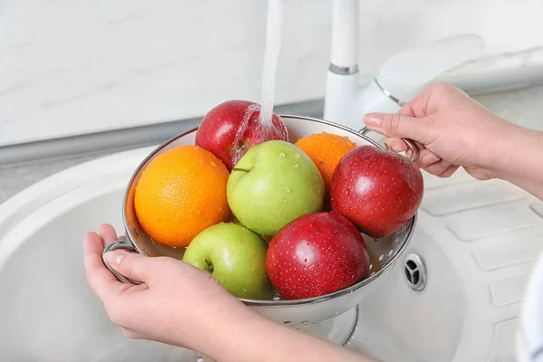 Mujer lavando frutas frescas en el colador bajo el agua, primer plano — Foto de Stock