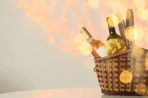 Cesta de mimbre con botellas de vino contra luces borrosas. Espacio para texto — Foto de Stock