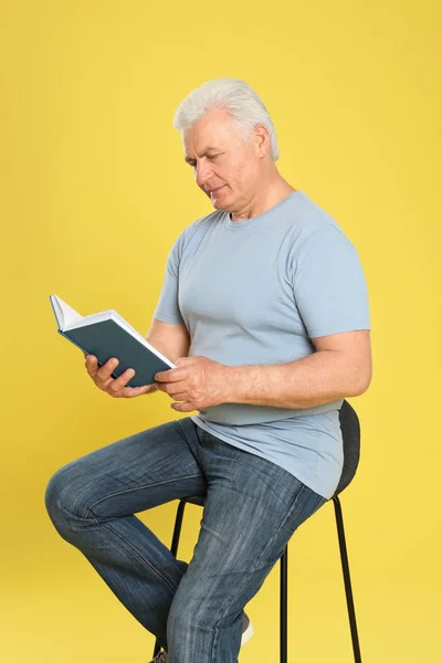 Старший читатель книги на цветном фоне — стоковое фото
