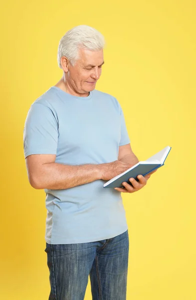 Hombre mayor leyendo libro sobre fondo de color —  Fotos de Stock