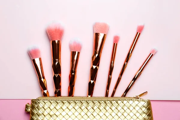 Saco com diferentes escovas de maquiagem no fundo de cor, flat lay — Fotografia de Stock