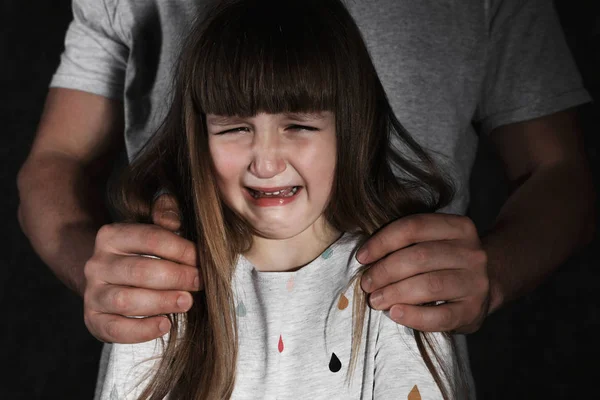 Crying little girl and adult man on dark background, closeup. Child in danger — Stock Photo, Image