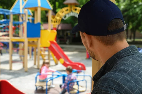 Sospettoso uomo adulto che spiava i bambini al parco giochi, spazio per messaggi. Bambino in pericolo — Foto Stock