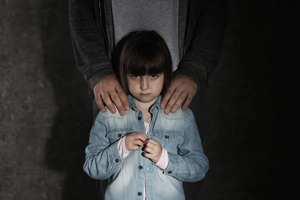 Menina assustada e homem adulto no fundo escuro. Criança em perigo — Fotografia de Stock