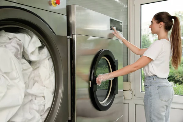 Ung kvinna trycka på knapparna på tvättmaskinen i kemtvätten — Stockfoto
