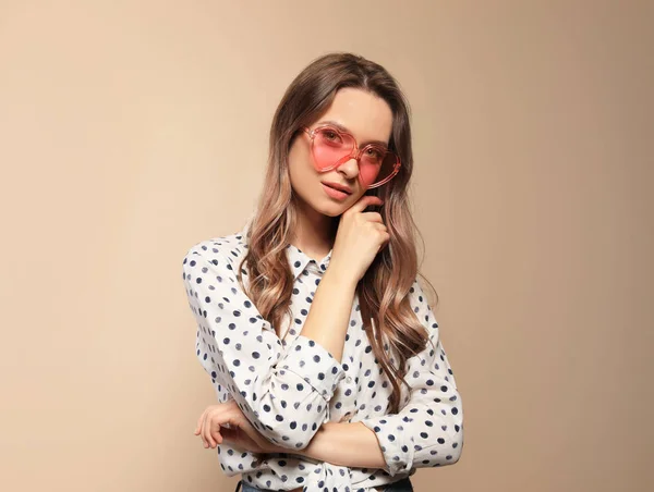 Retrato de una hermosa mujer joven con gafas de sol en forma de corazón sobre fondo de color — Foto de Stock