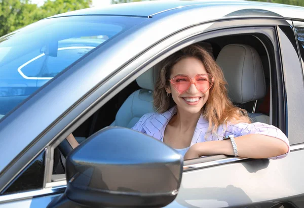 Happy woman with heart shaped glasses in car