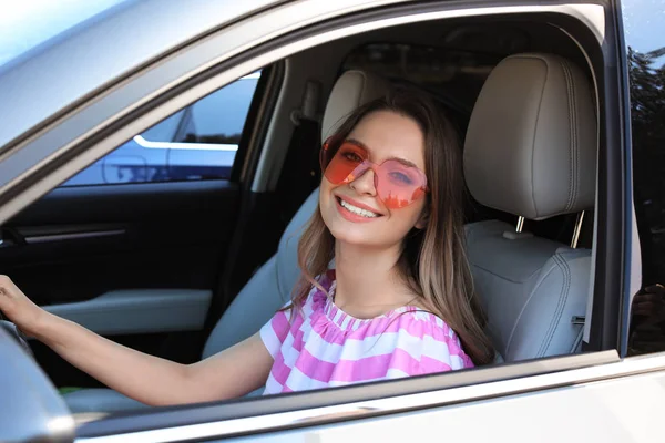Happy woman with heart shaped glasses in car — Stock Photo, Image