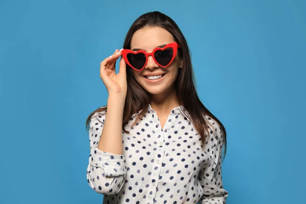 Porträtt av vacker ung kvinna med hjärtformade solglasögon på färg bakgrund — Stockfoto
