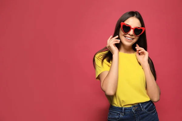 Portret van mooie jonge vrouw met hartvormige zonnebril op kleur achtergrond. Ruimte voor tekst — Stockfoto
