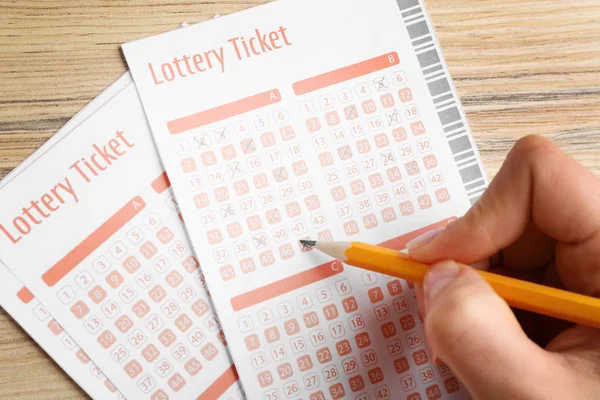 Mulher preenchendo bilhetes de loteria com lápis na mesa de madeira, close-up. Espaço para texto — Fotografia de Stock