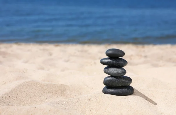 Stack di pietre sulla sabbia vicino al mare, spazio per il testo. Concetto zen — Foto Stock