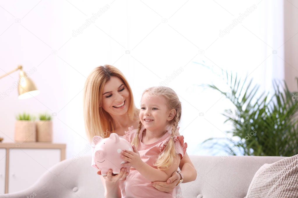 Mother and daughter with piggy bank at home