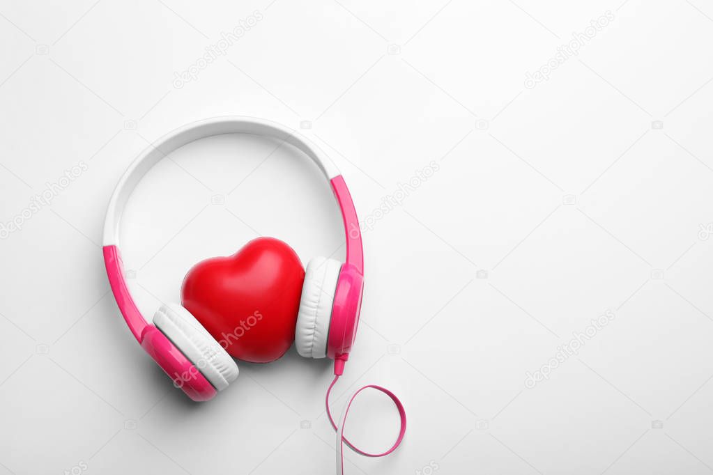 Decorative heart and modern headphones on white background, top view