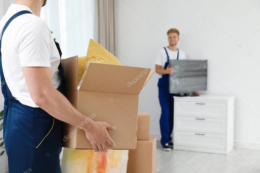 Moving service employee with box and his colleague in room, closeup